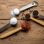 Farklı baharatlarla dolu ölçü kaşıkları ahşap masa üzerinde